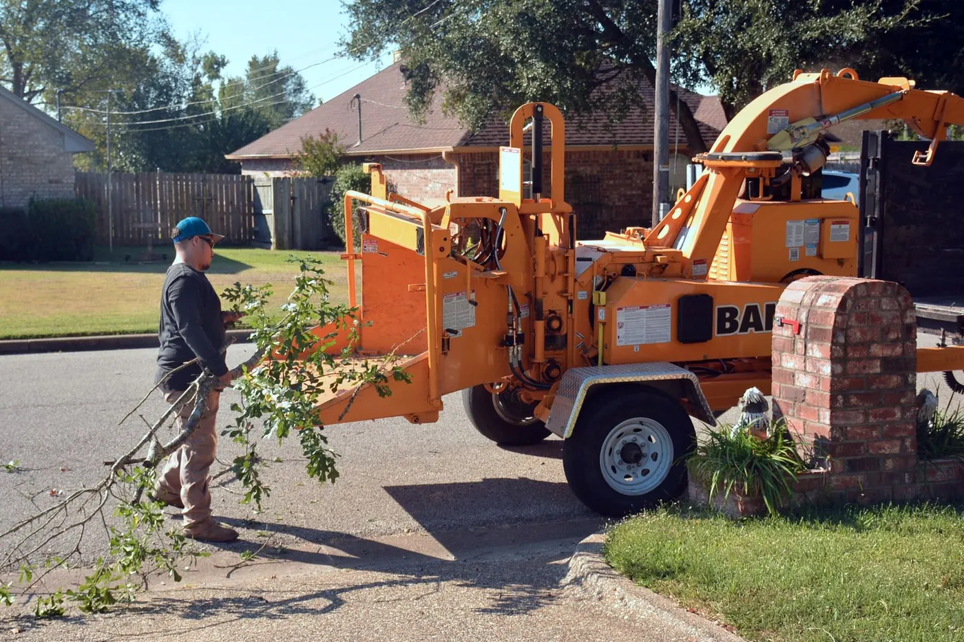 a wood chipper and a worker clearing brush